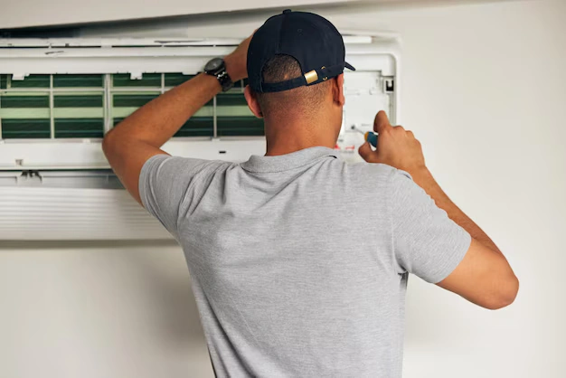 AC repair technician tightening components on a wall mounted unit while completing a professional AC tune up for a DFW homeowner