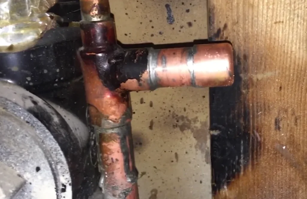 Corroded copper pipe fittings with visible mineral buildup under a home, a warning that helps explain slab leak signs and repair cost for DFW homeowners