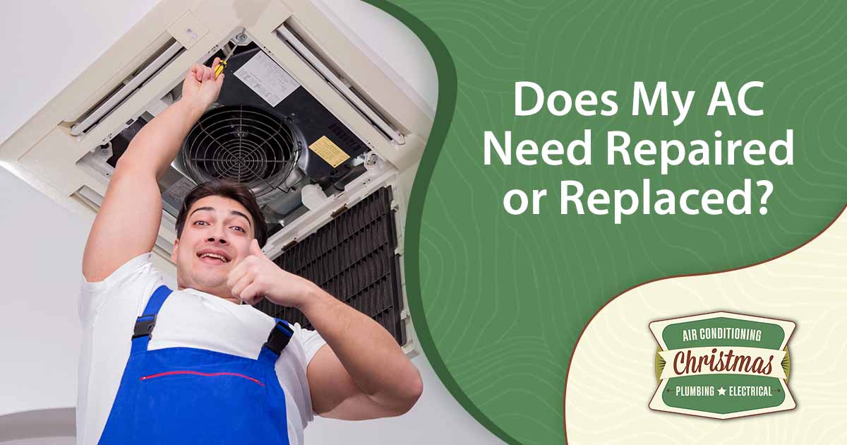 Worker repairing a ceiling air conditioning unit, featuring Christmas Airconditioning and Heating and highlighting "Does My AC Need Repaired or Replaced?" ensuring it aligns with the page's context.
