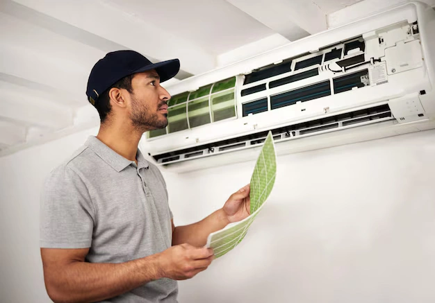HVAC technician inspecting a clean air filter as part of an AC maintenance checklist homeowners can follow each season