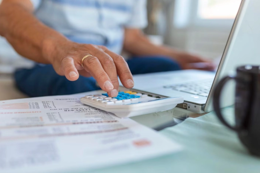 Homeowner using a calculator to add up cooling costs and find ways to reduce summer AC expenses in the DFW area