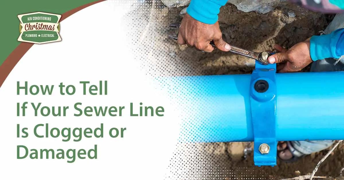 Image of a man using a large wrench on water pipes at a construction site, featuring Christmas Air Conditioning and Plumbing and highlighting how to tell if your sewer line is clogged or damaged.