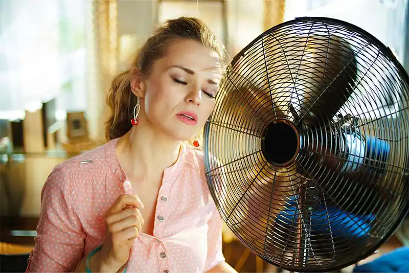 Woman in front of a fan waiting on Christmas Air Conditioning and Heating because her air conditioner is broken.
