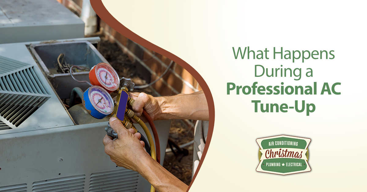 Technician using manifold gauges to check refrigerant pressure during an AC tune-up.