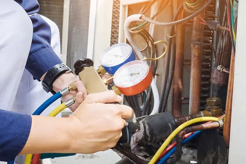 HVAC Maintenance - man adjusting the pressure on an HVAC system