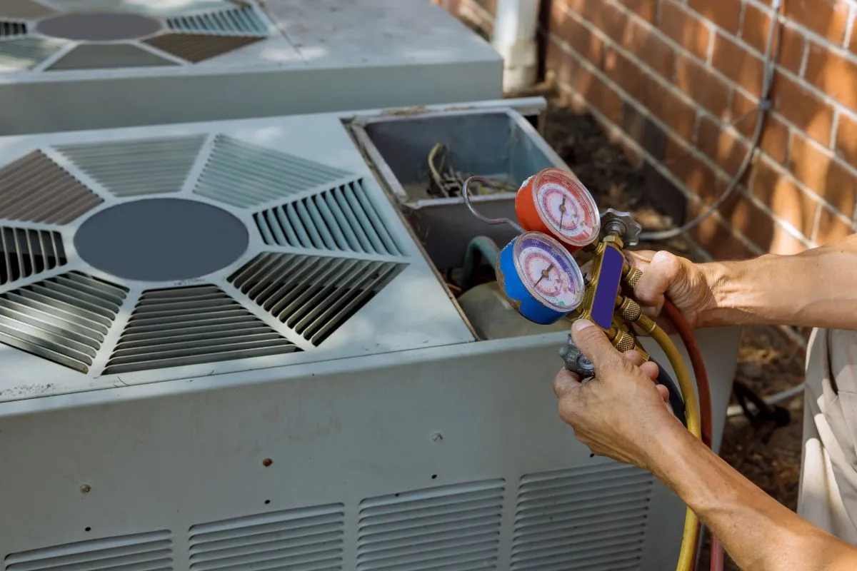 How much does AC repair cost in Texas technician checking refrigerant with gauge manifold