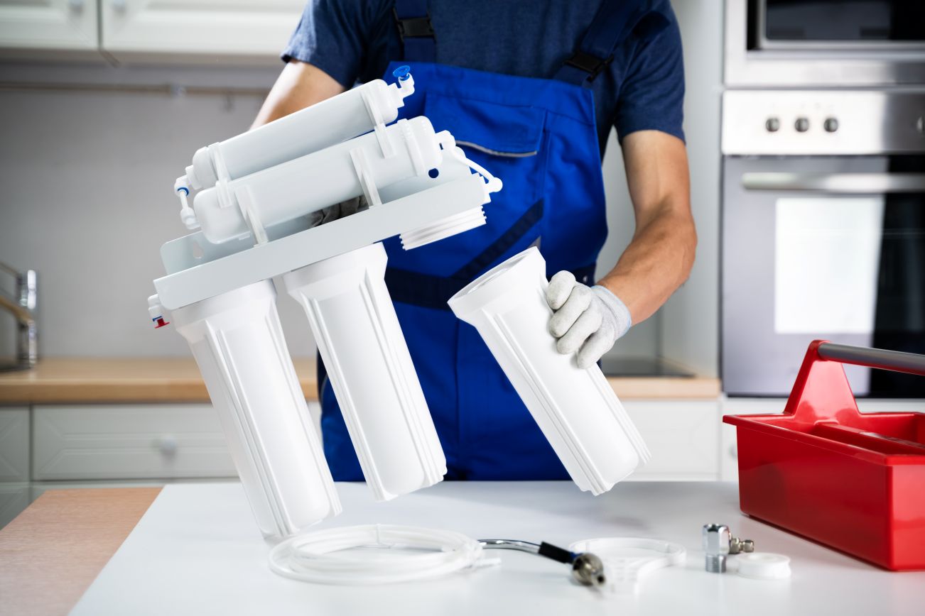 water filtration needs Image of a water filtration repairman at work, featuring Christmas Air Conditioning and Plumbing and highlighting water filtration system services.