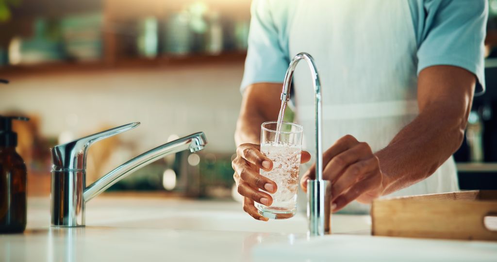 water filtration services Image of a man getting water, featuring Christmas Air Conditioning and Plumbing and highlighting water filtration for clean and safe drinking water.
